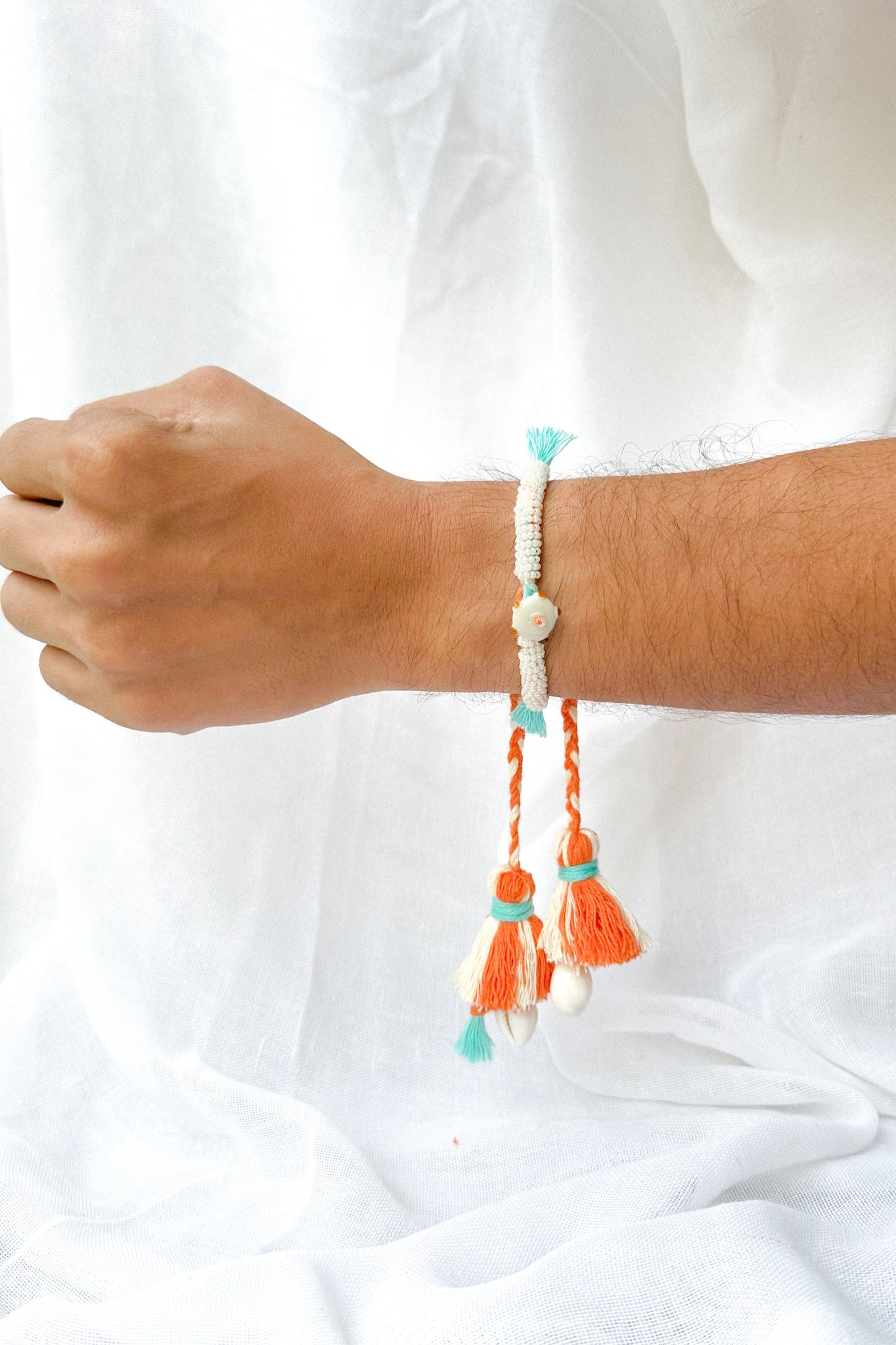 Bracelet with tassels on a wrist against a white background