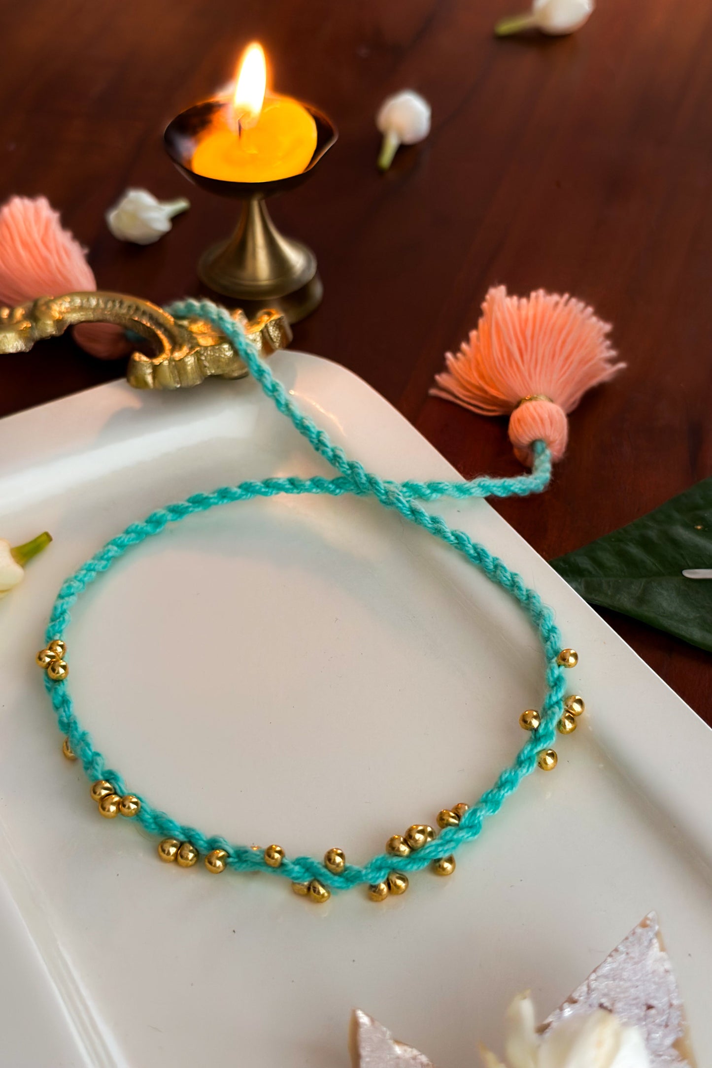 Turquoise bracelet with gold beads on a white surface with decorative elements.