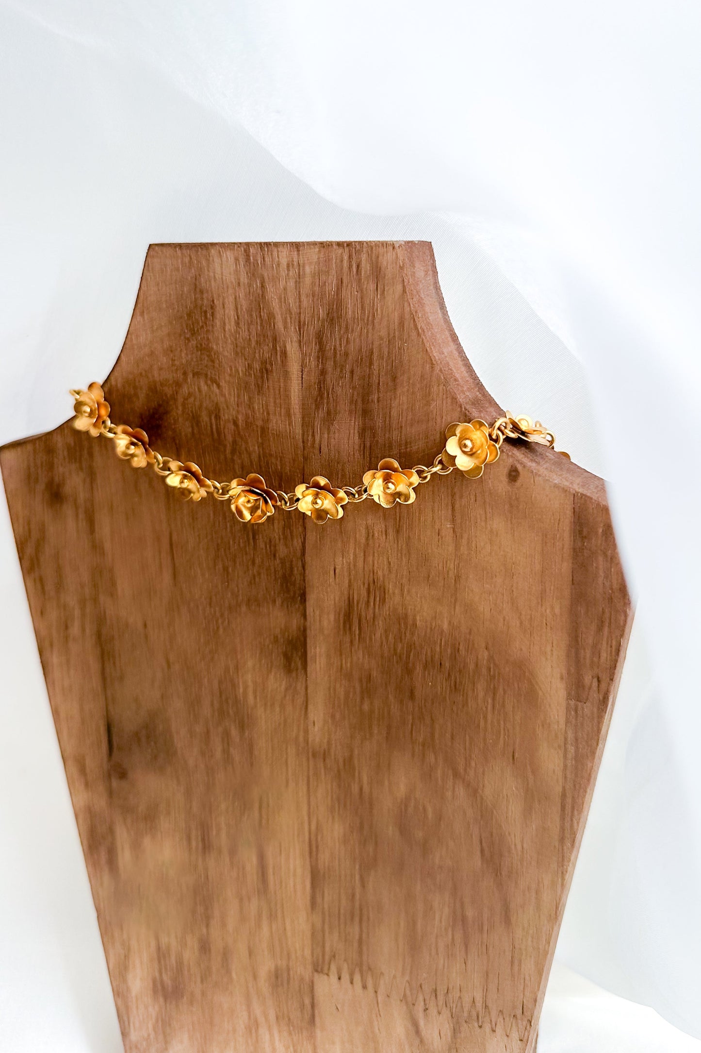 Gold necklace on a wooden mannequin bust with a white background
