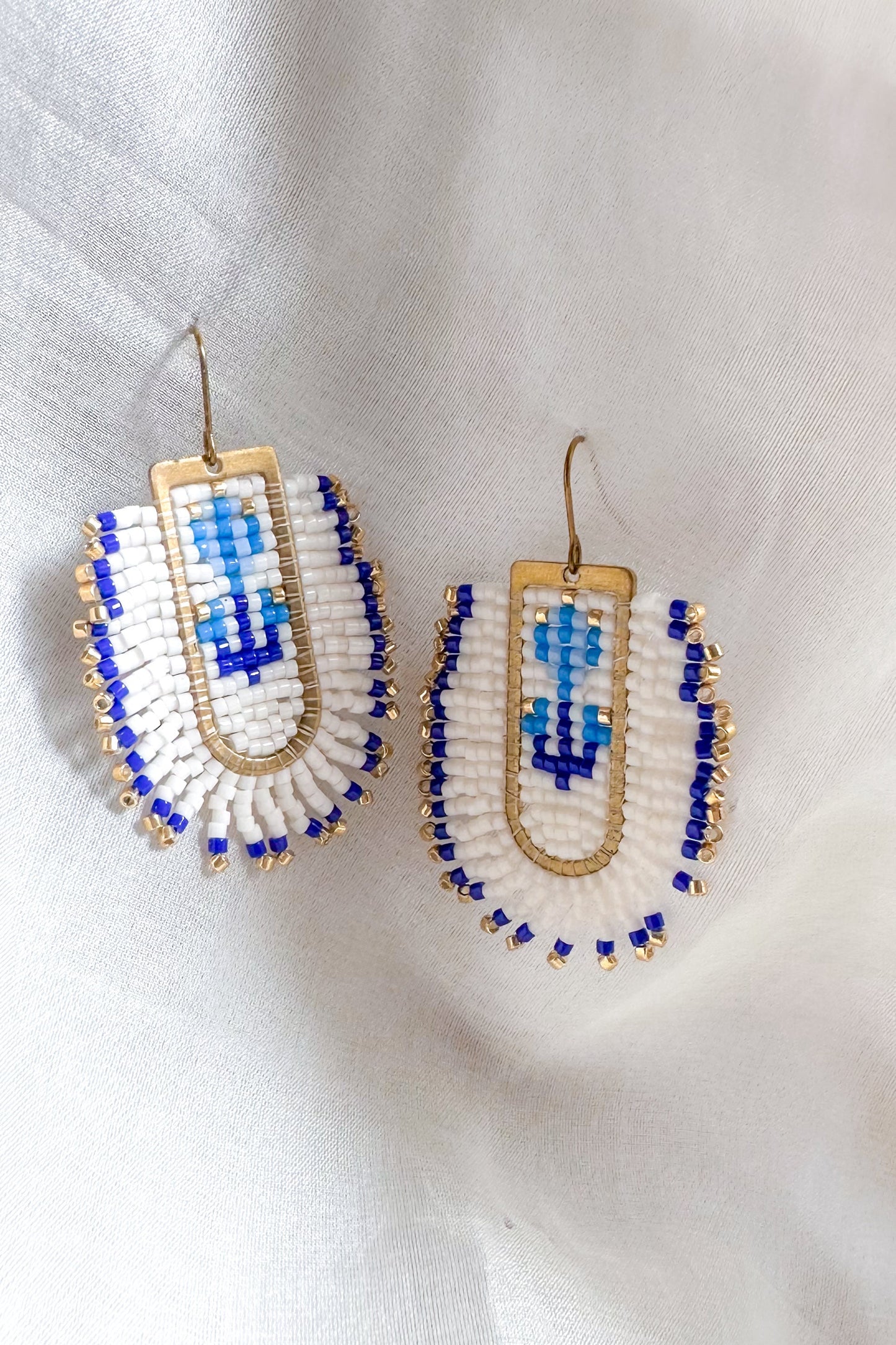 Pair of beaded earrings with blue and white design on a light background