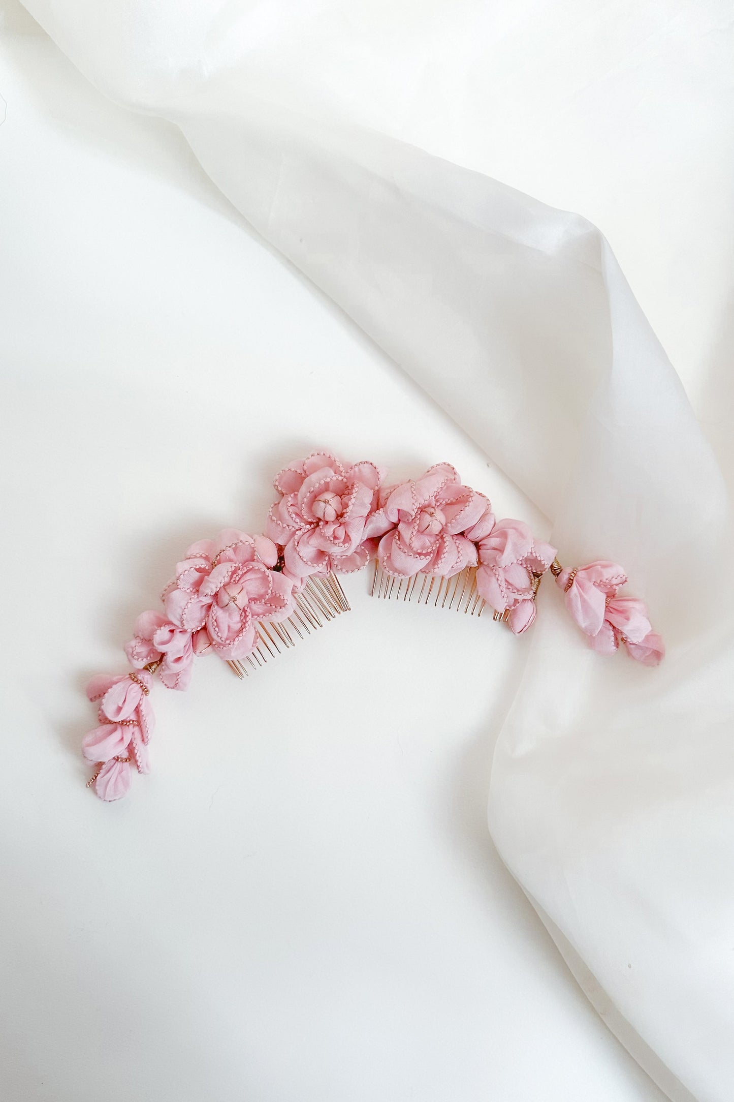 Pink floral hair comb on a white fabric background