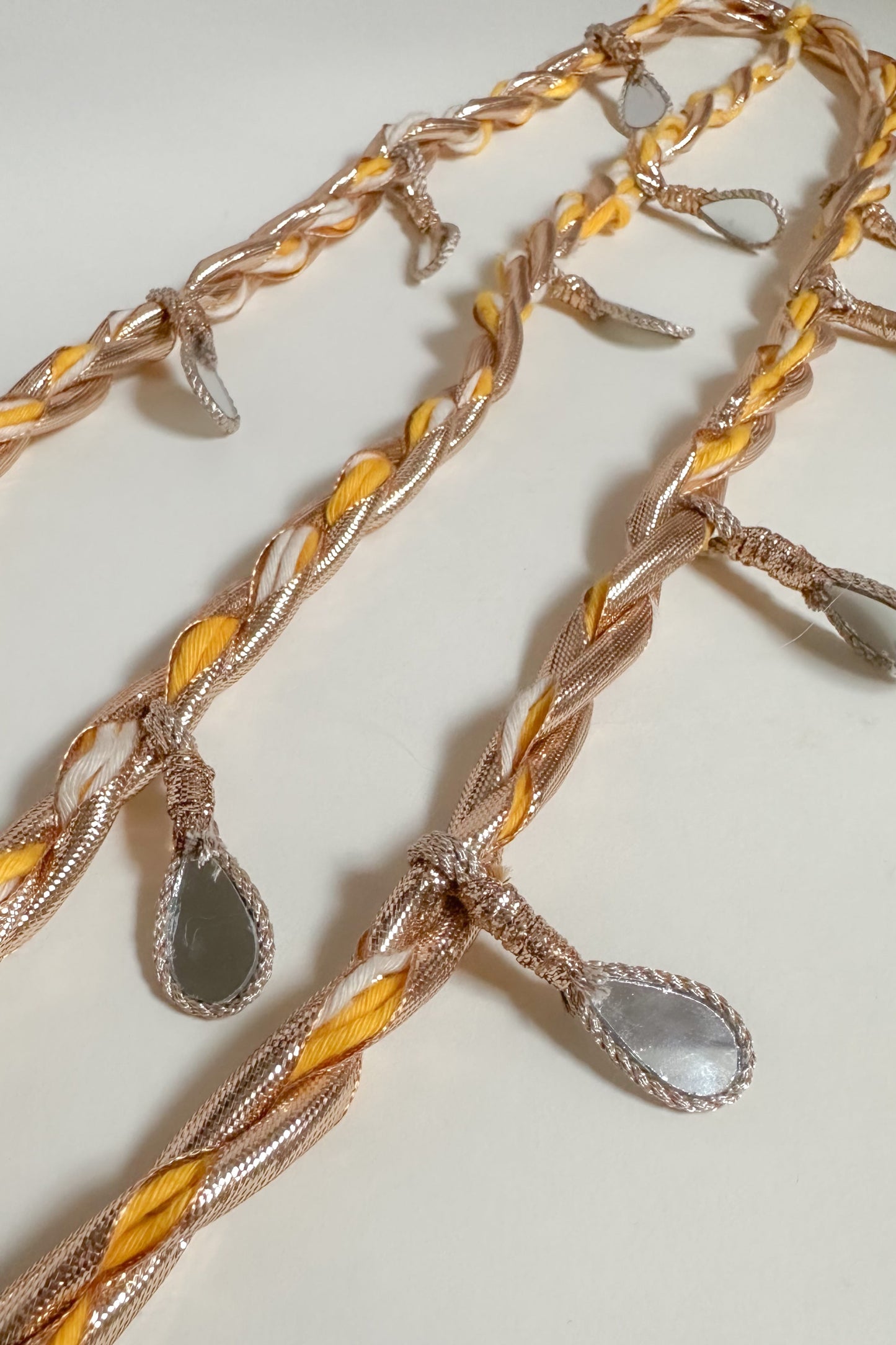 Parandi with braided design and teardrop-shaped pendants on a light background