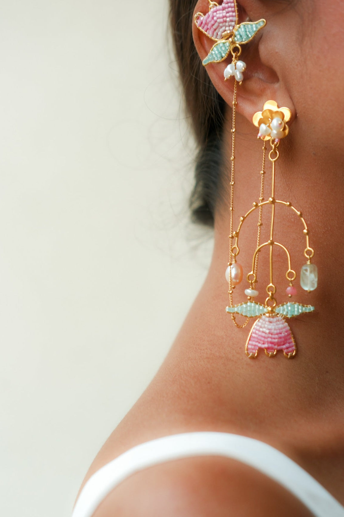 Close-up of a person wearing colorful earrings with a white top.