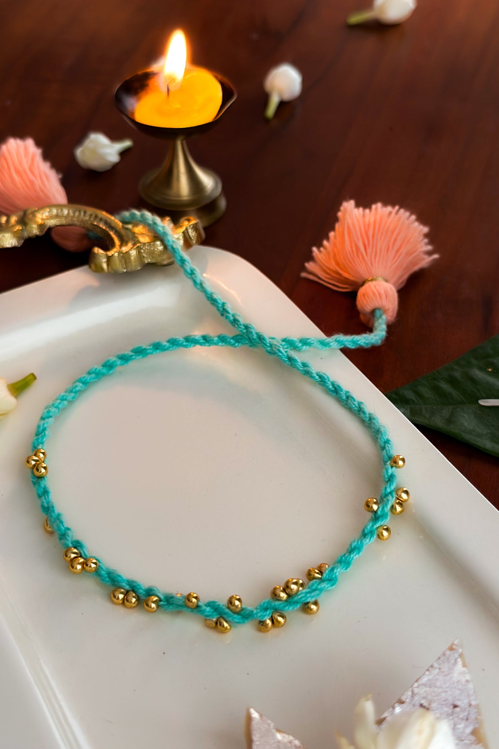 Turquoise bracelet with gold beads on a white surface with decorative elements.