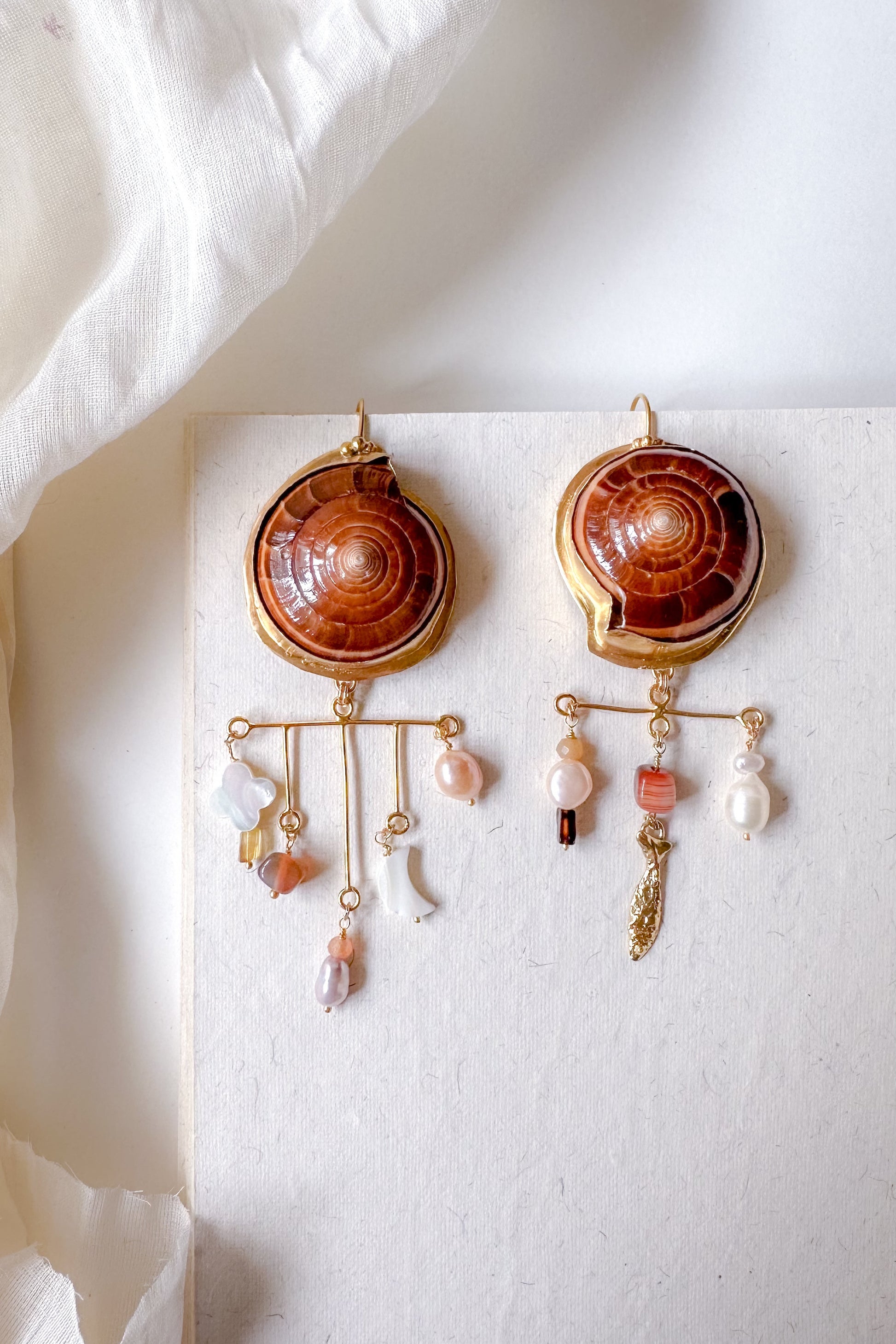 Pair of earrings with shell design and pearls on a white background
