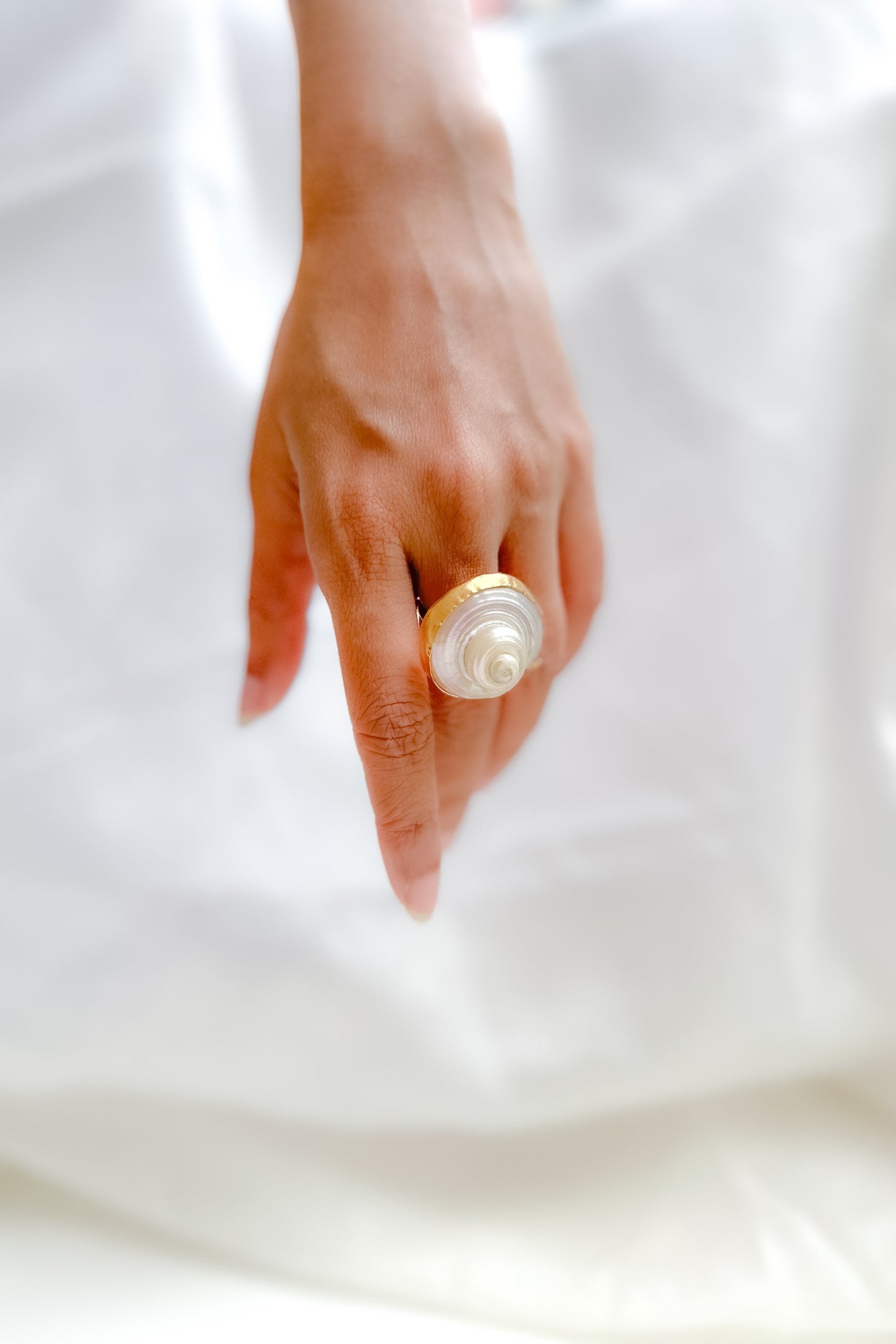Hand wearing a pearl ring on a white background
