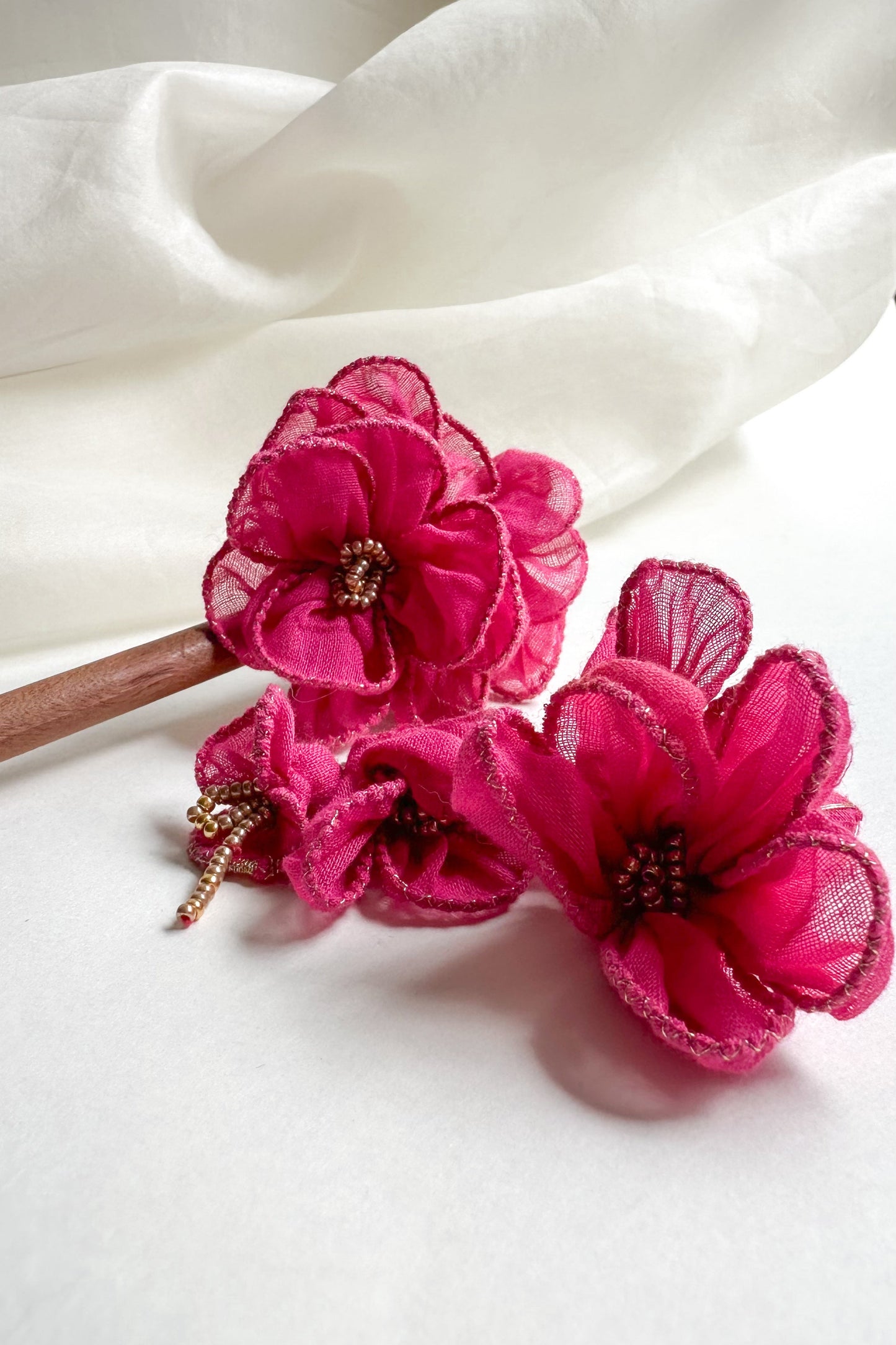 Pink floral hair clips on a white fabric background