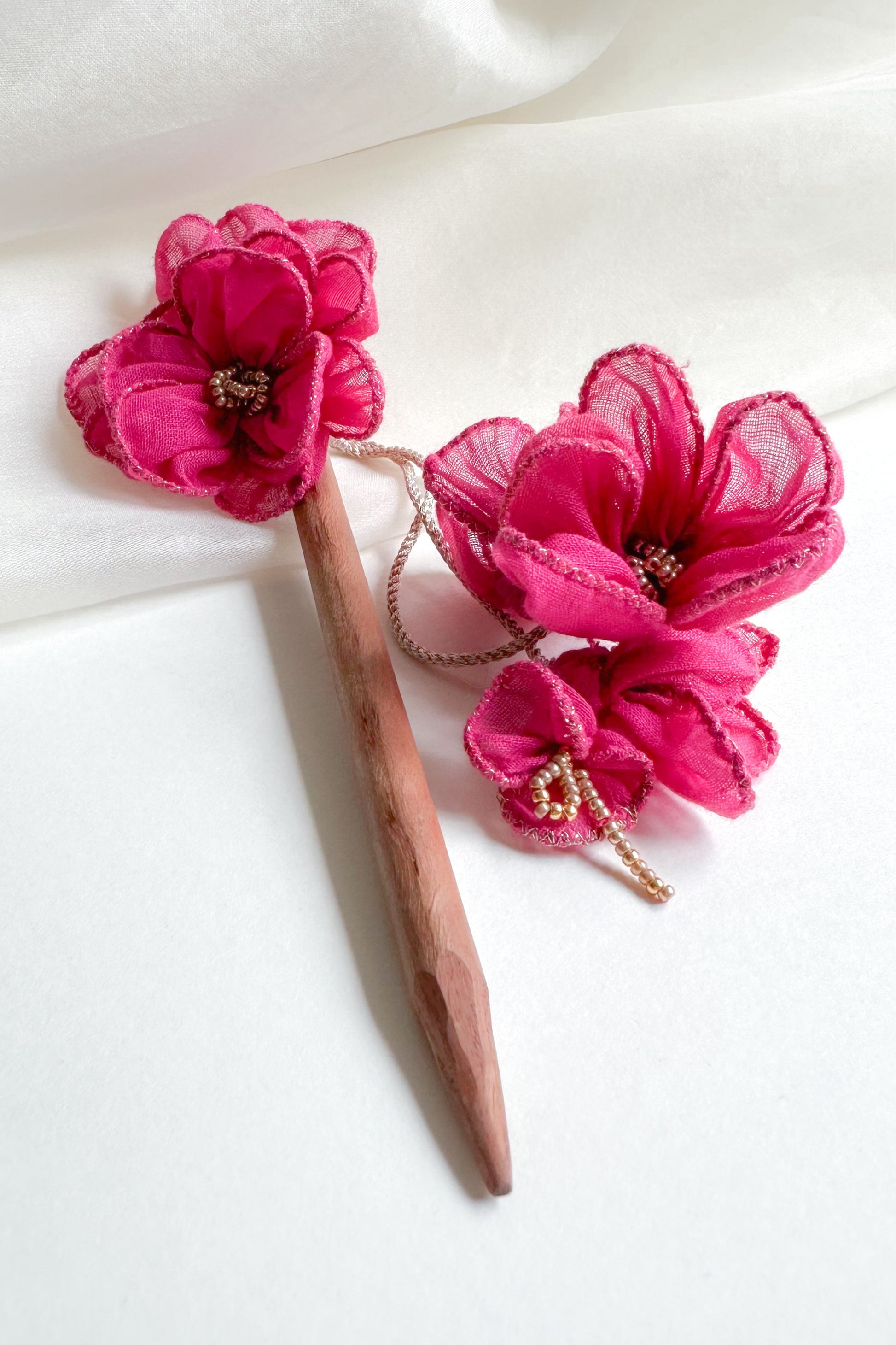 Pink floral hair accessories on a white fabric background