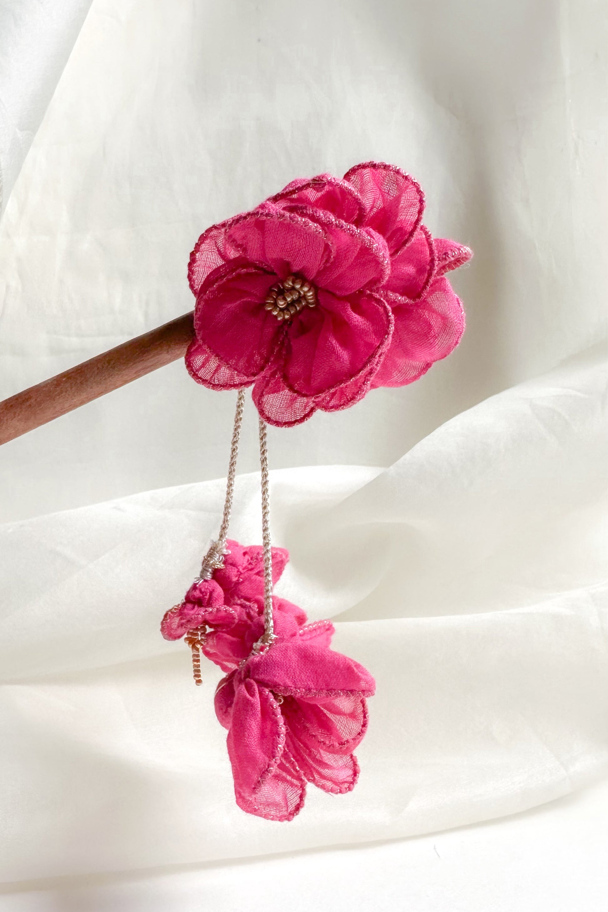 Pink floral hair pin on a white fabric background