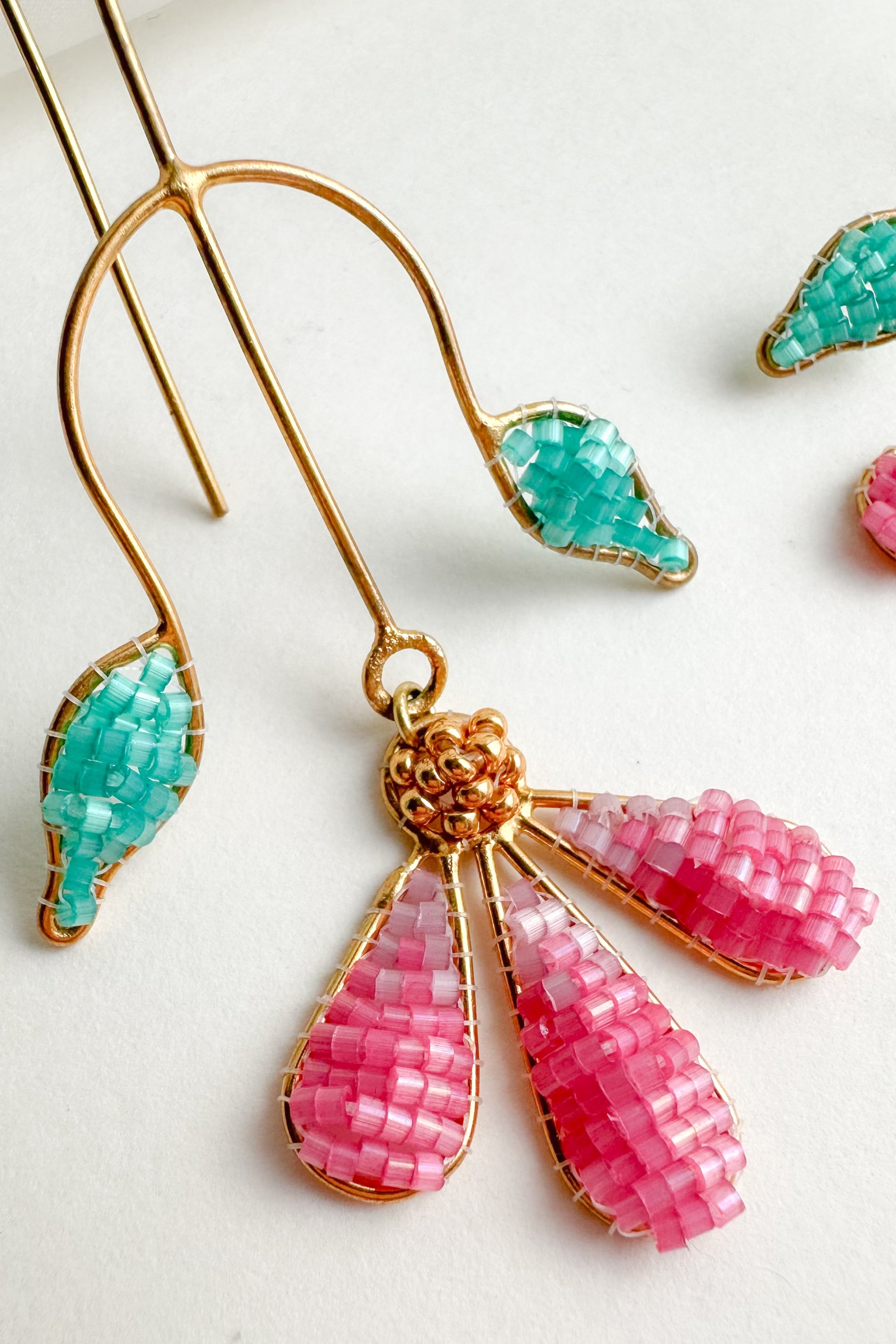 Earrings with pink and green beads on a light background