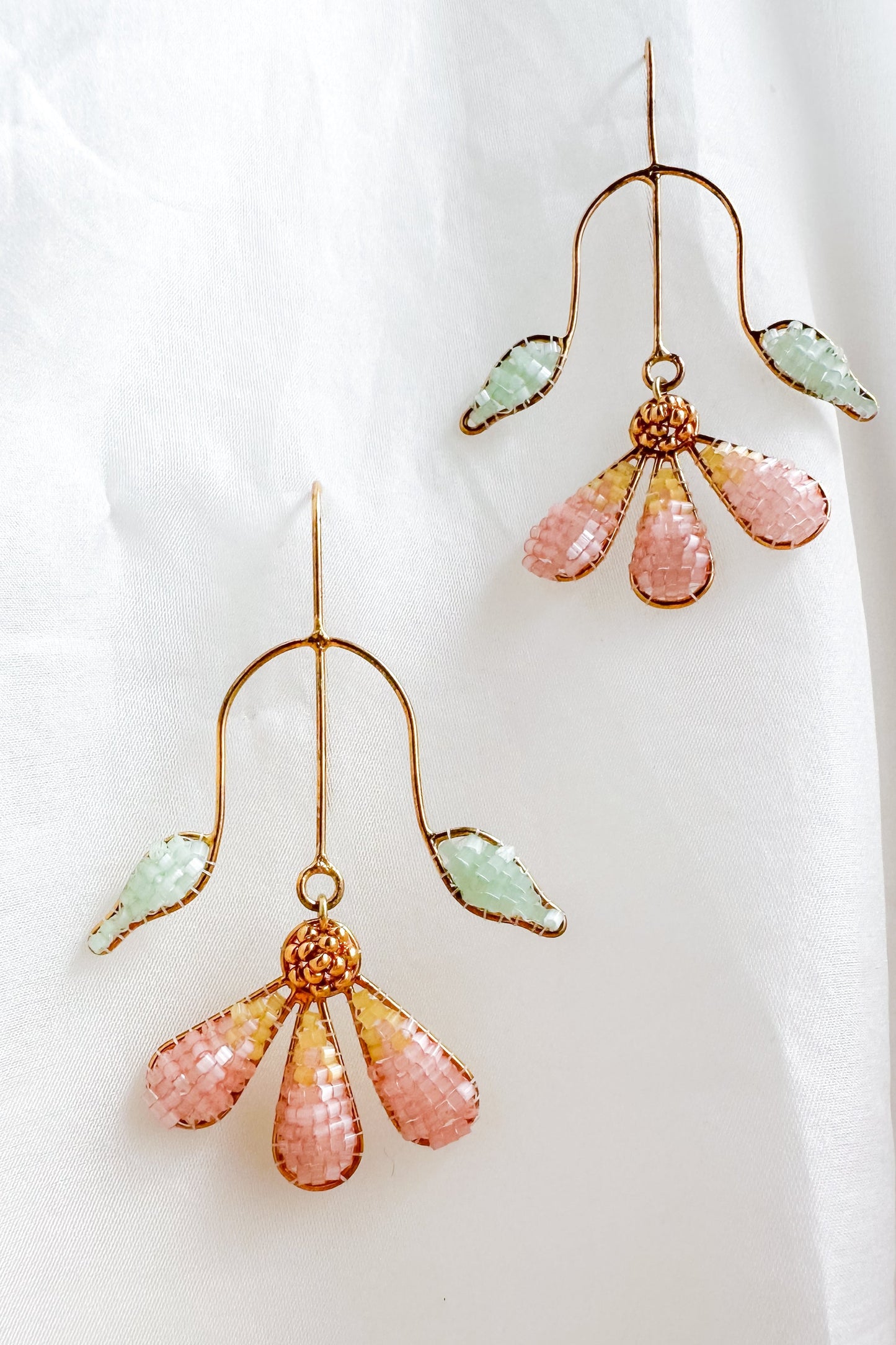Pair of earrings with pink and green glass beads on a white background
