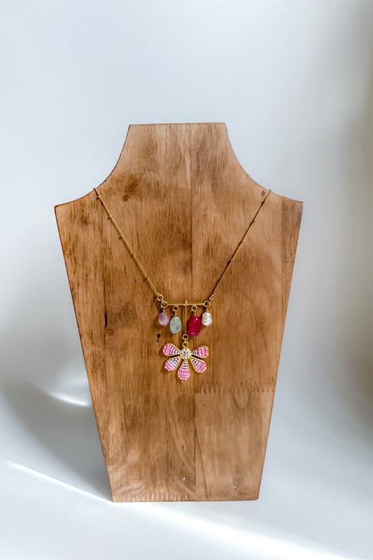 Necklace with colorful pendant on a wooden mannequin bust against a white background