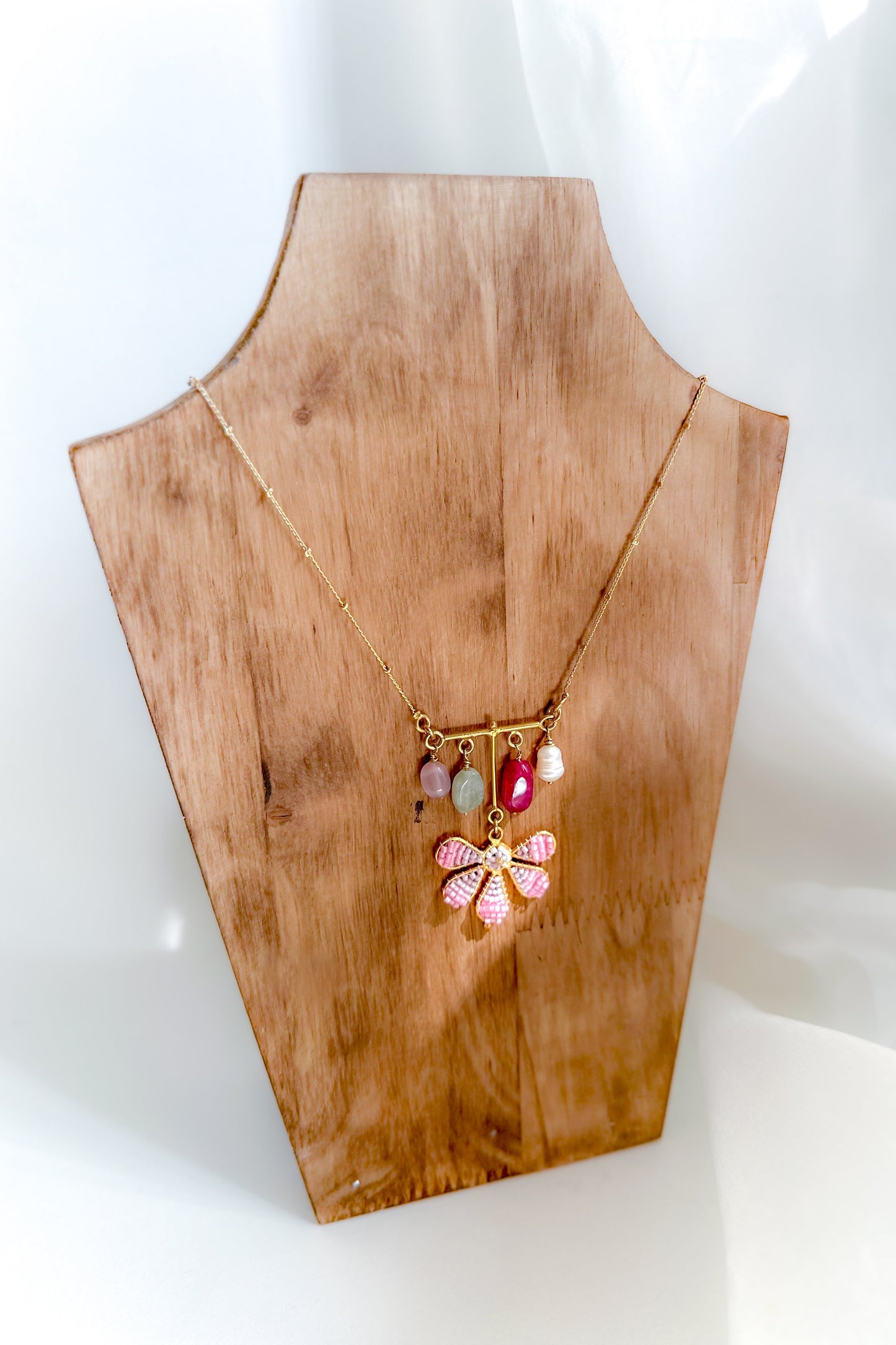 Necklace with colorful pendant on a wooden mannequin bust against a white background