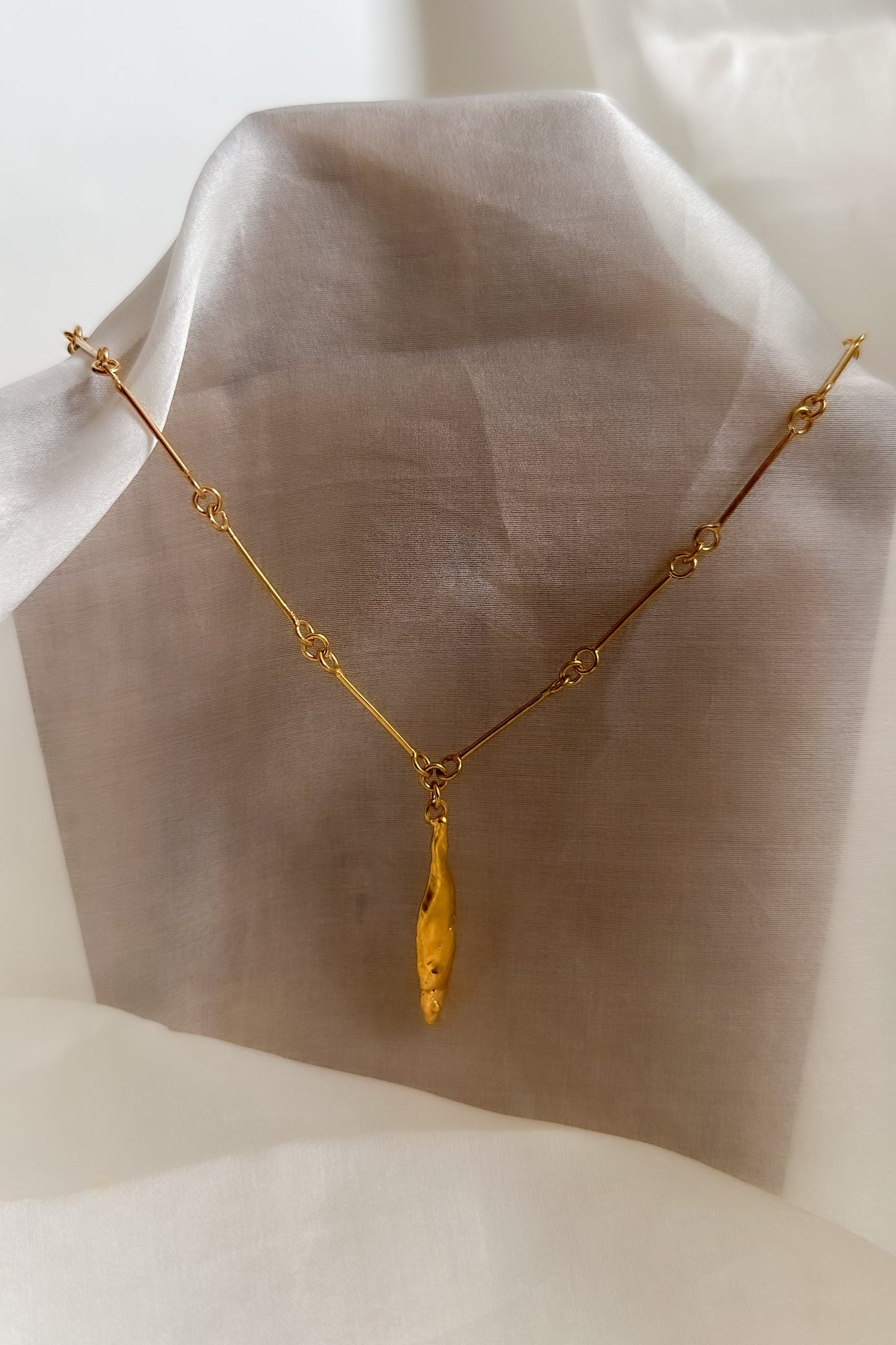 Gold necklace on a white fabric background