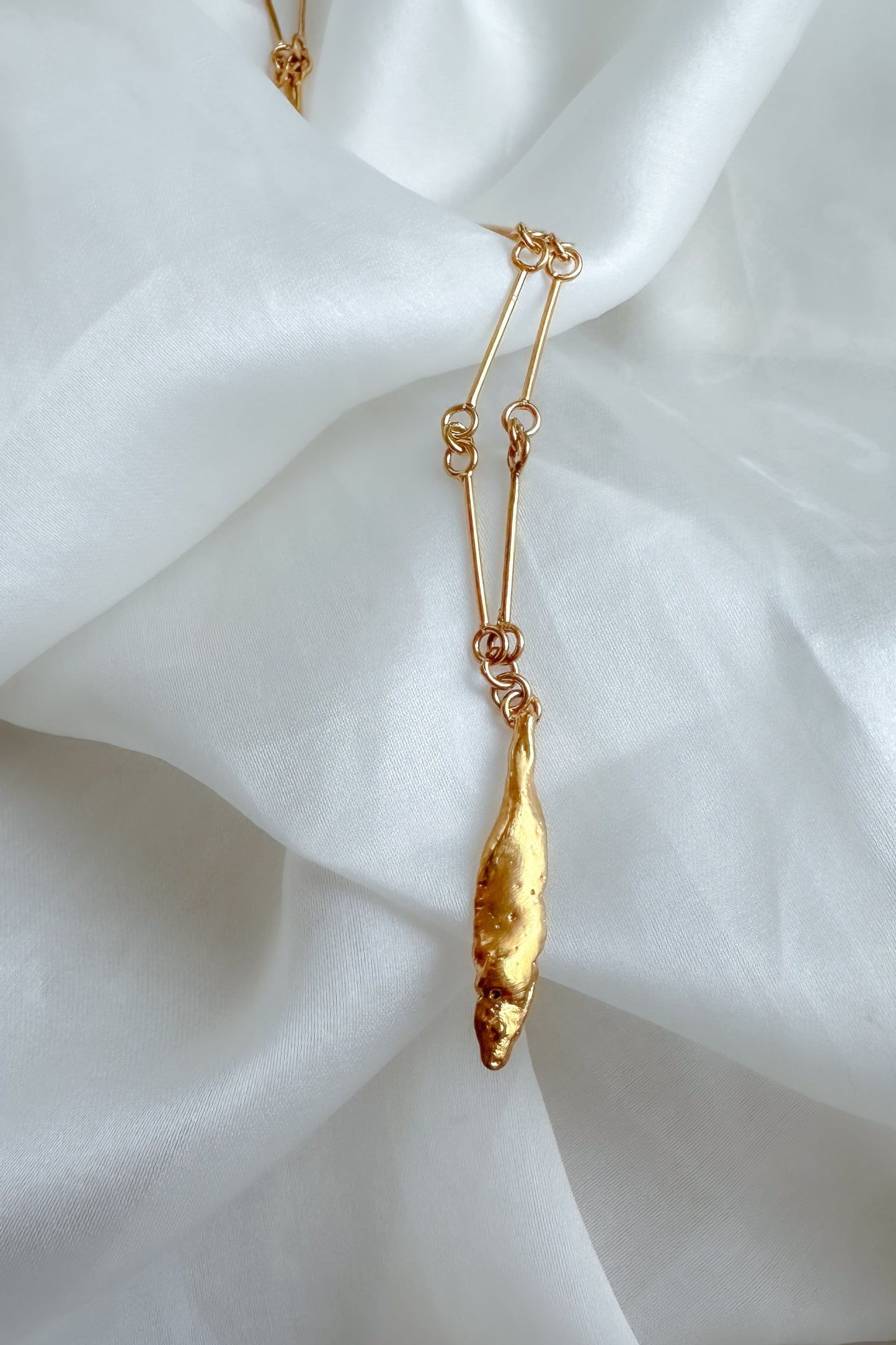 Gold necklace with a pendant on a white fabric background