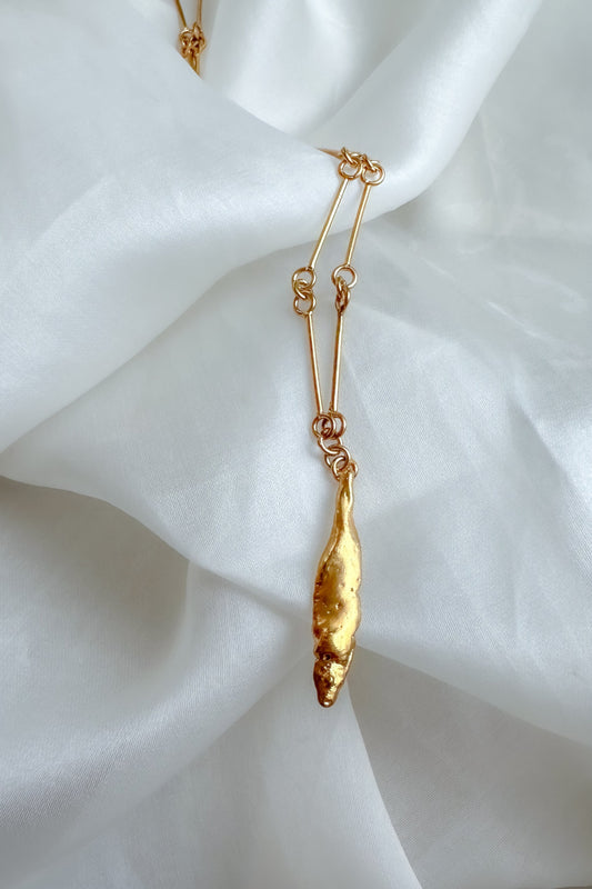 Gold necklace with a pendant on a white fabric background