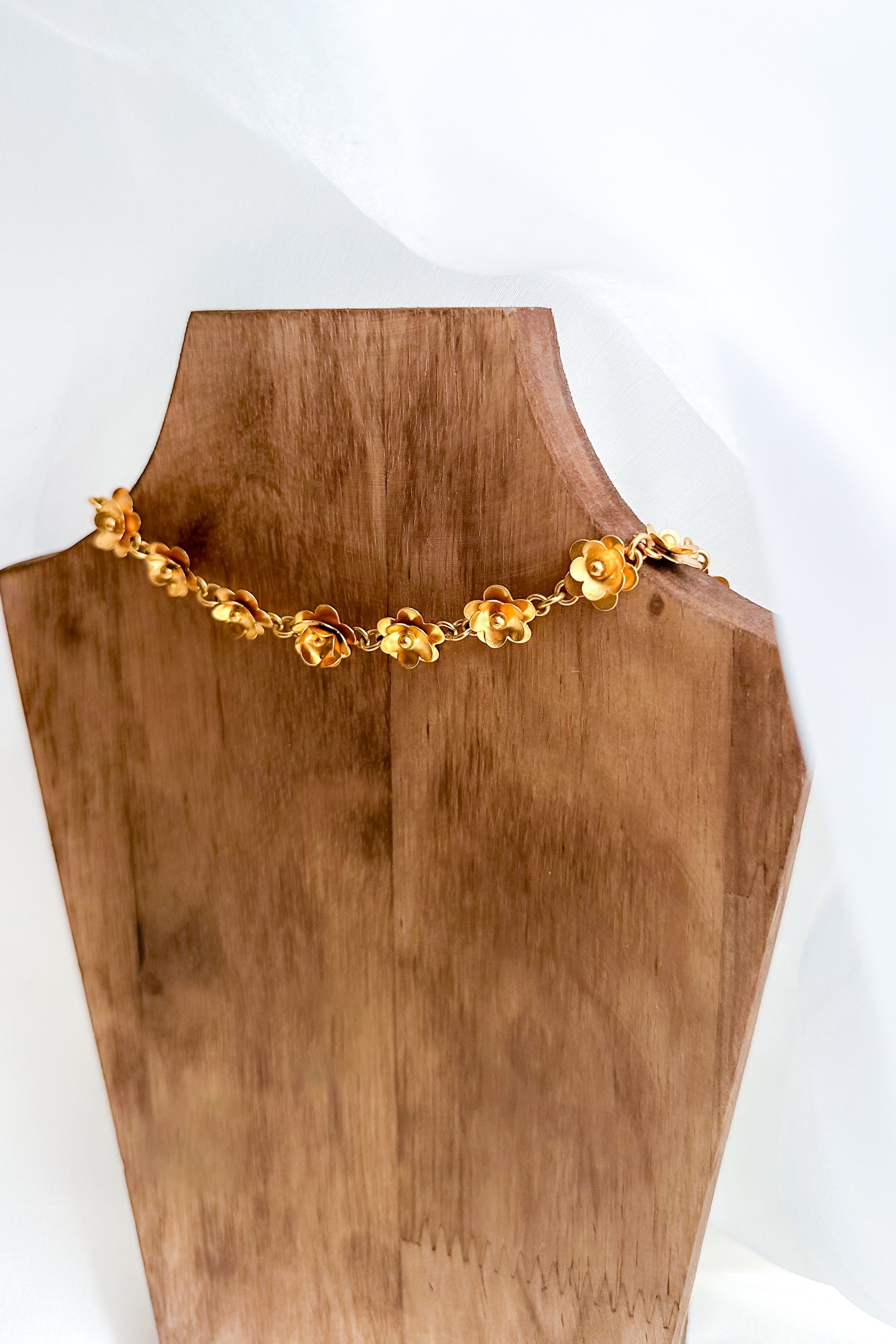 Gold necklace on a wooden mannequin bust with a white background