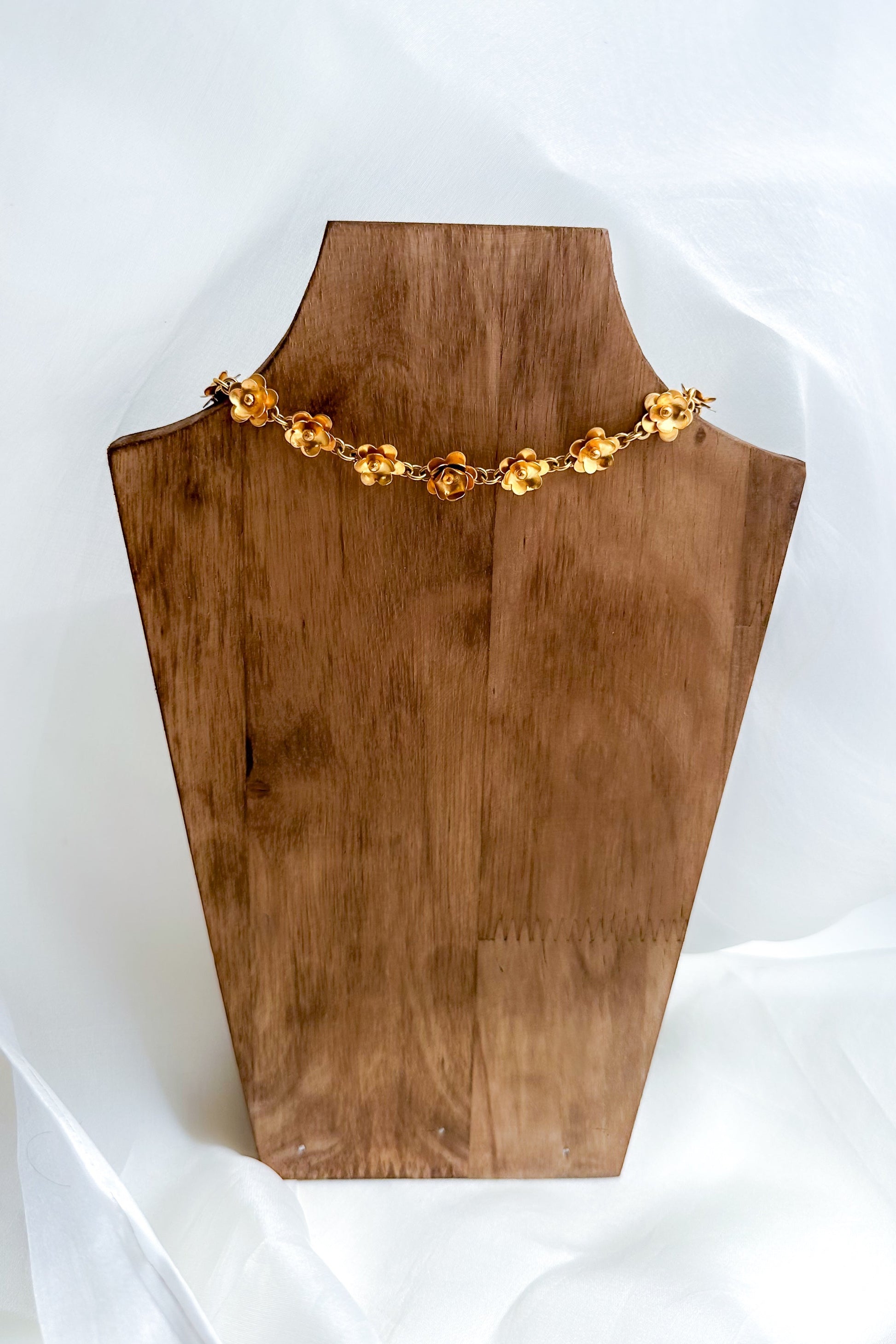 Necklace displayed on a wooden mannequin bust against a white background