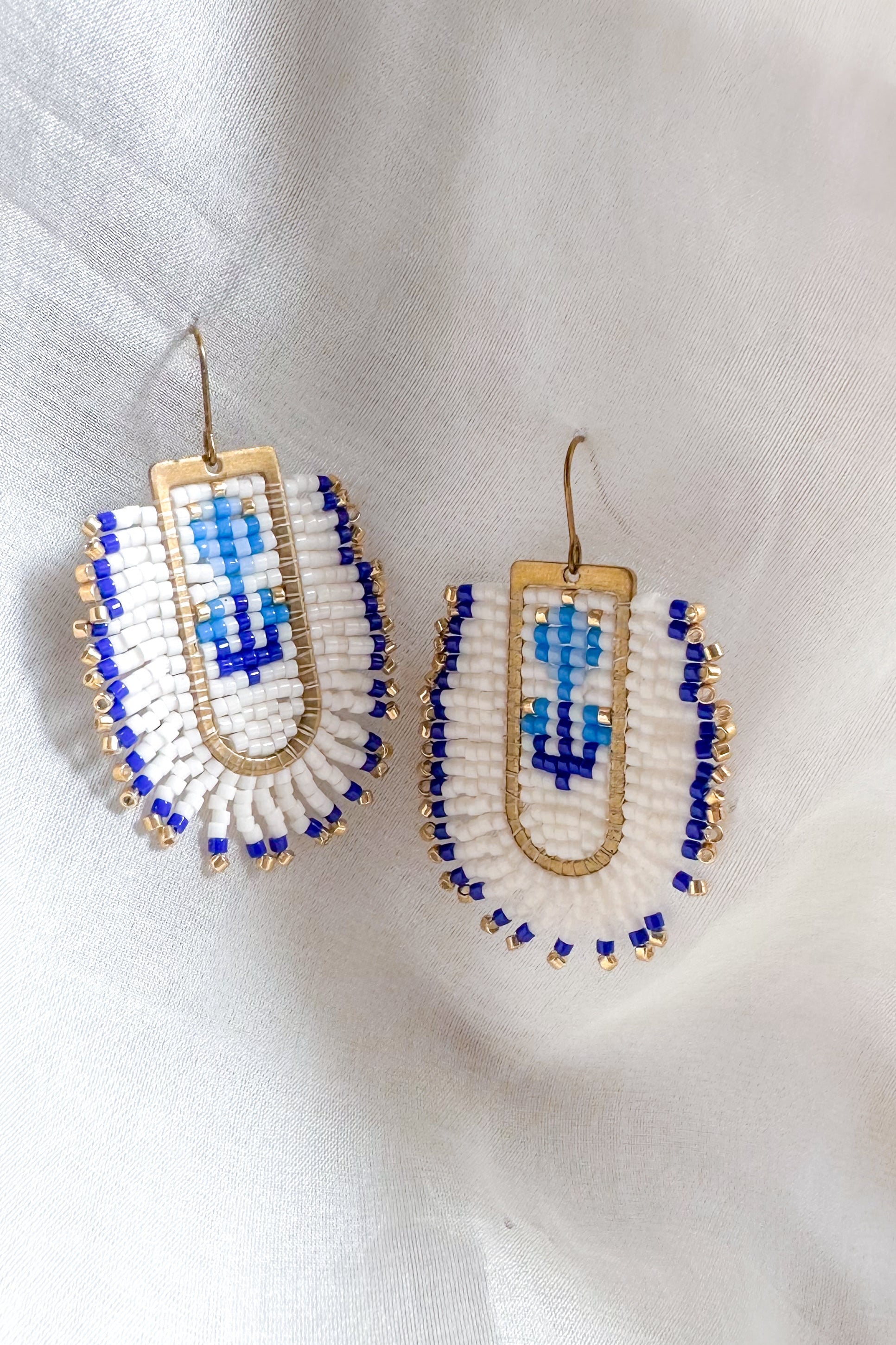 Pair of beaded earrings with blue and white design on a light background