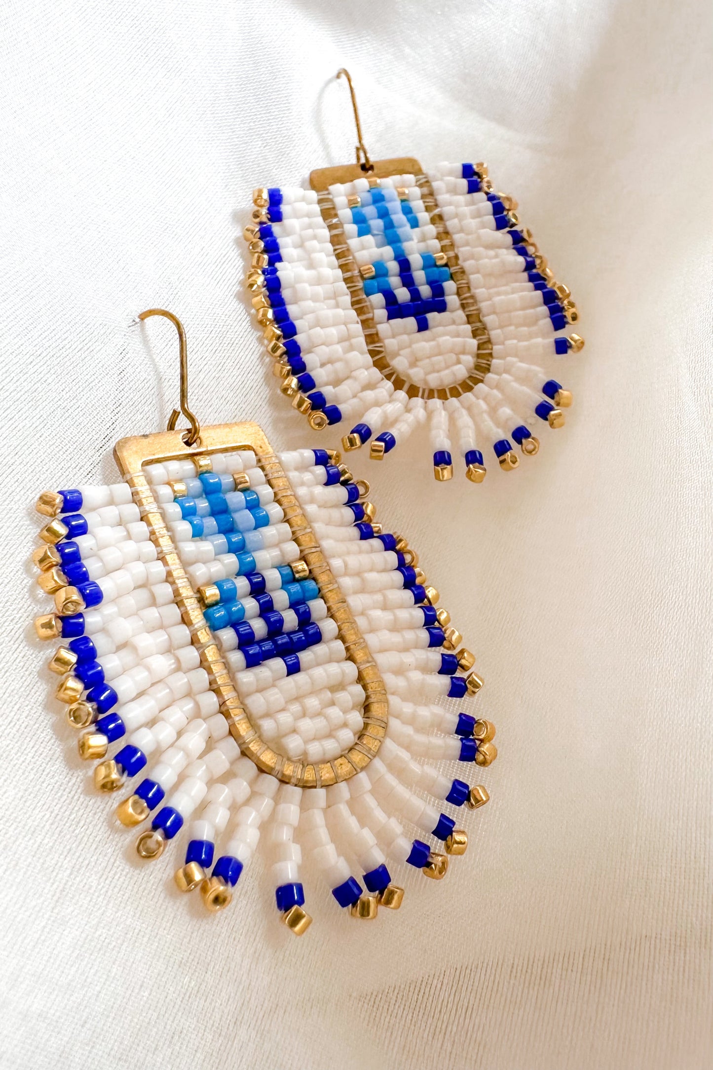 Pair of beaded earrings with blue and gold accents on a white background