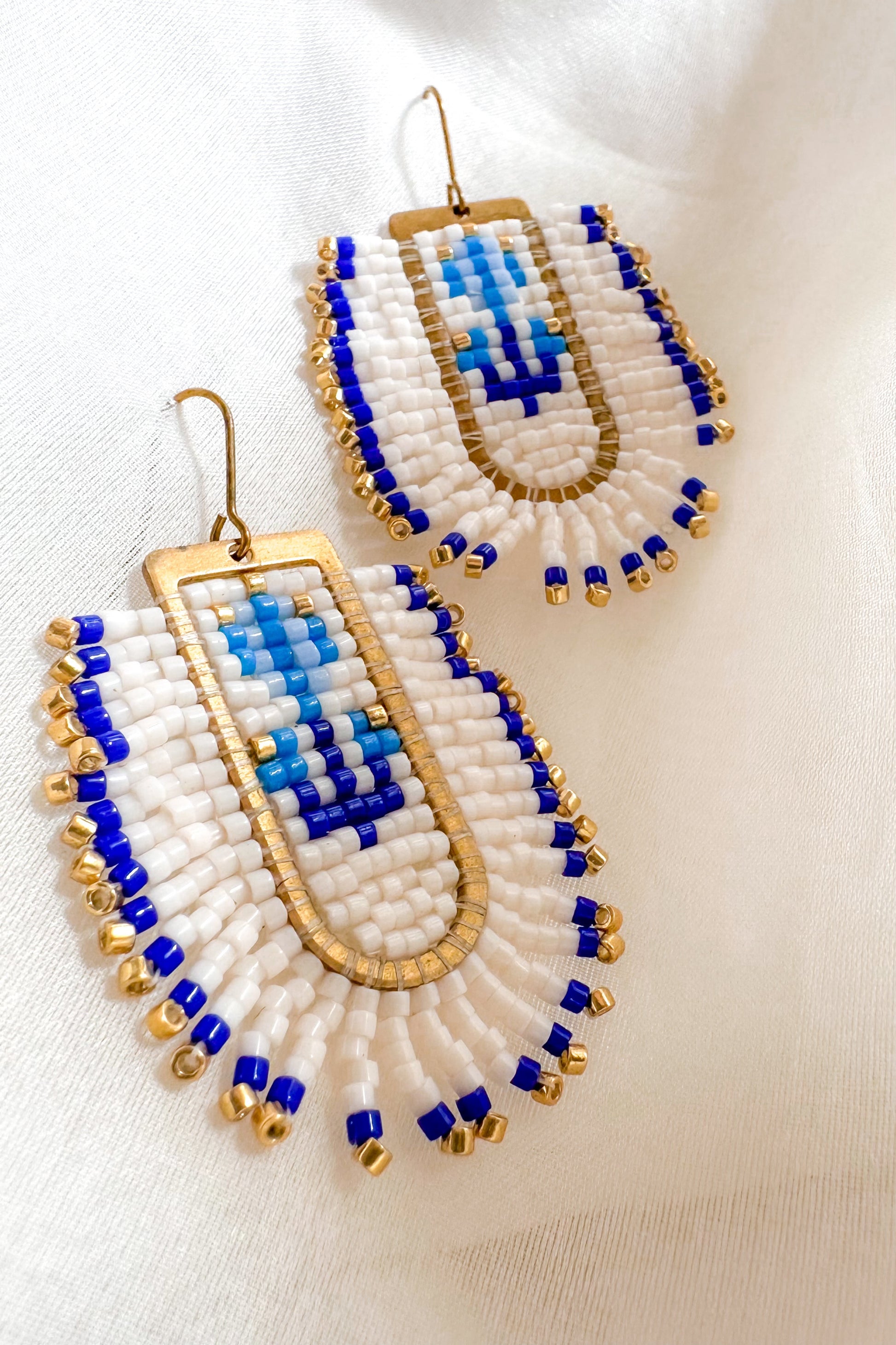 Pair of beaded earrings with blue and gold accents on a white background