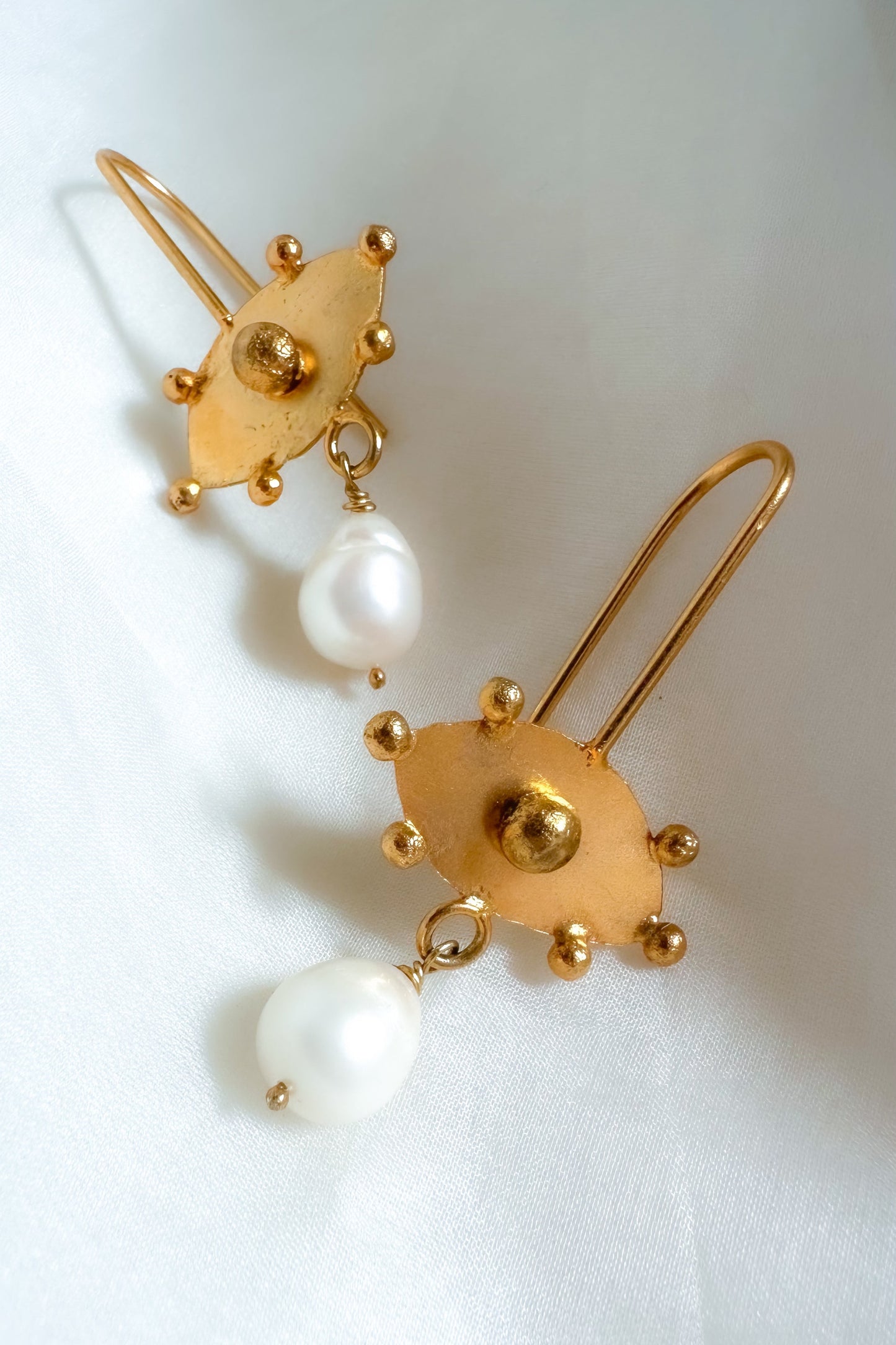 Gold earrings with pearl drops on a white background
