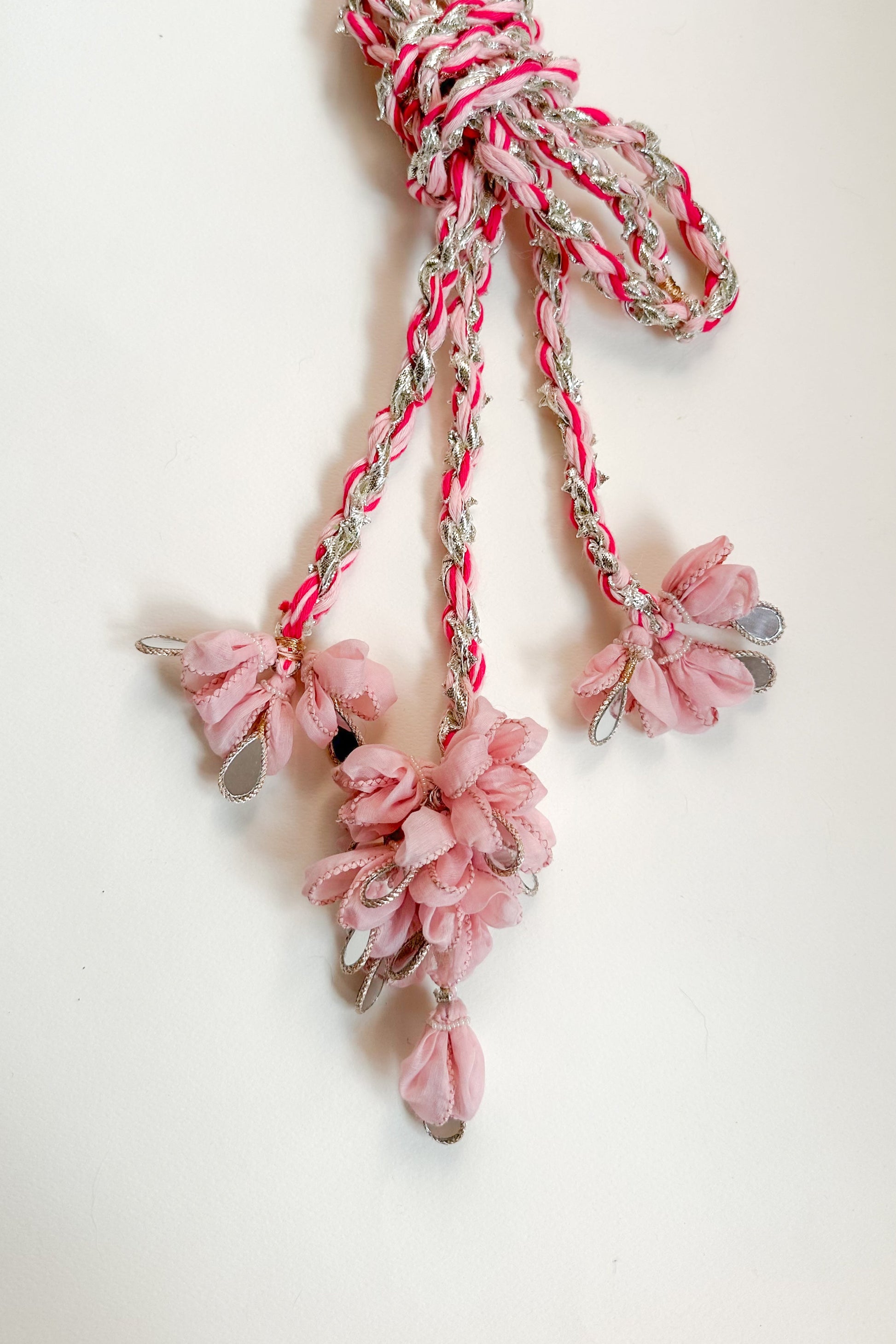 Braided parandi with pink floral & mirror attachments on a white background