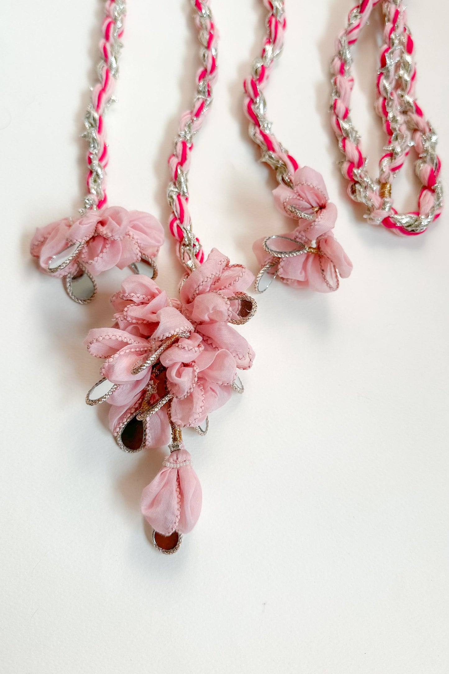 Braided Parandi with pink floral pendant and braided pink and silver chain on a white background