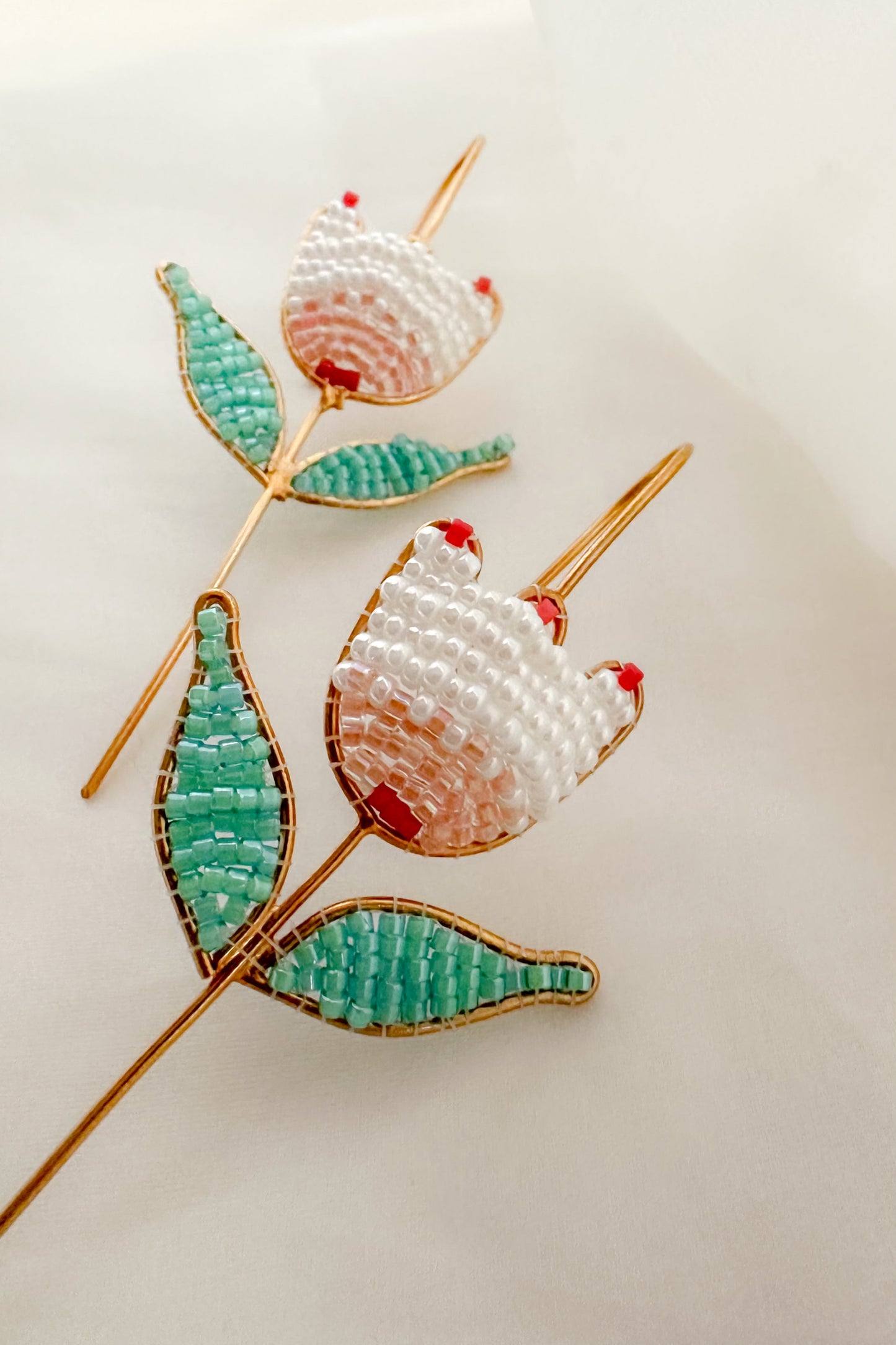 Decorative Earcuff with beaded tulip motif on a light background