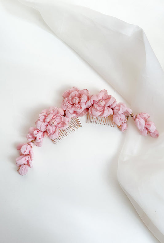 Hair comb with pink floral attachments on a white fabric background