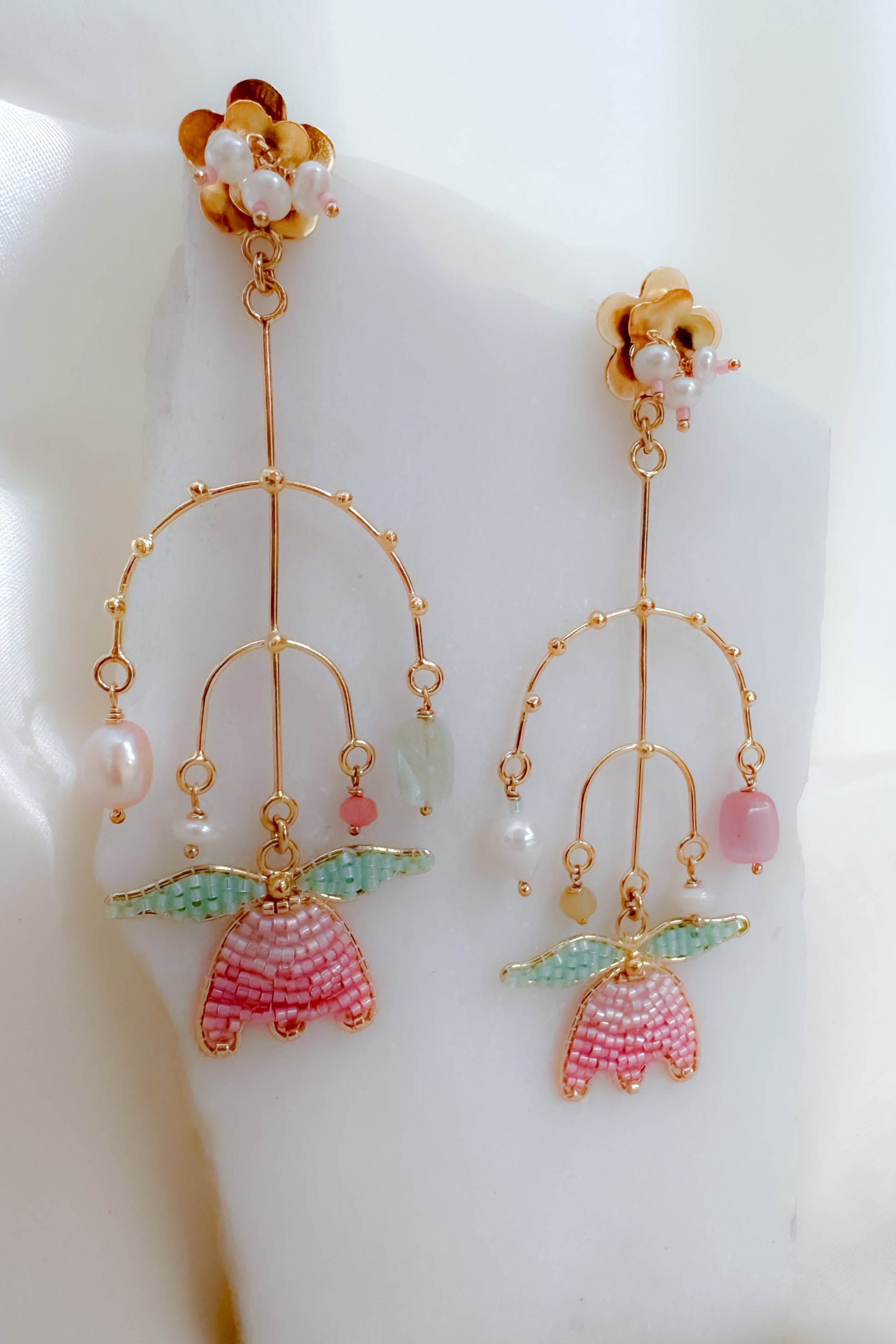 Delicate earrings with floral designs and colorful beads on a white background