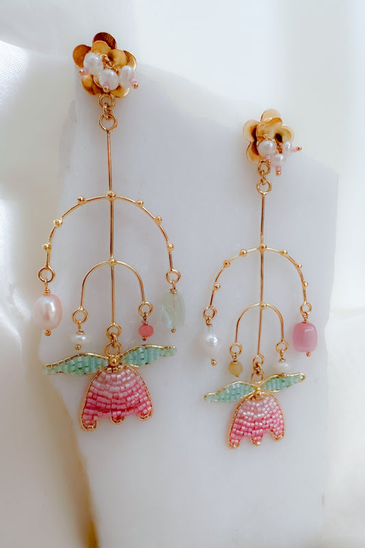 Delicate earrings with floral designs and colorful beads on a white background