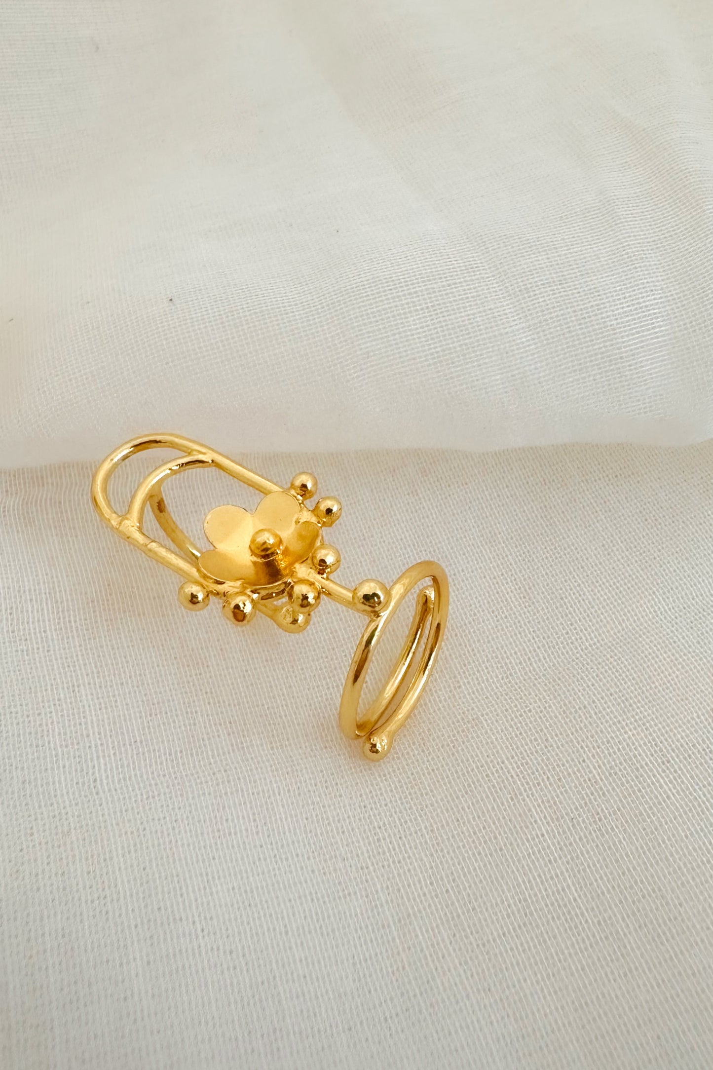 Gold decorative nail ring on a beige fabric background