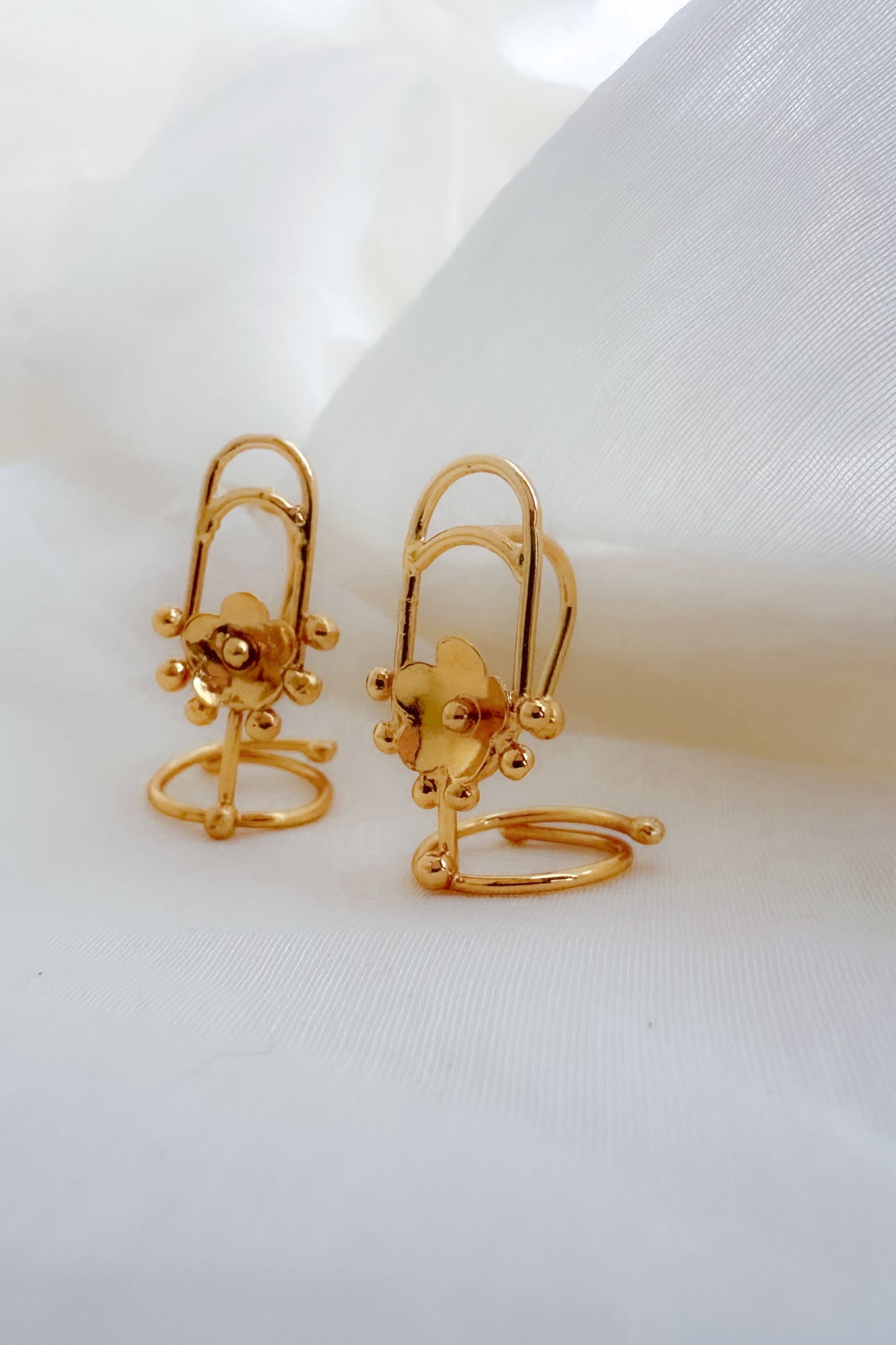 Pair of gold nail rings  on a white fabric background